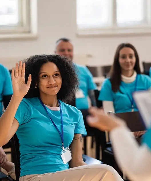 Female nurse in scrubs with her hand raised in a group training session