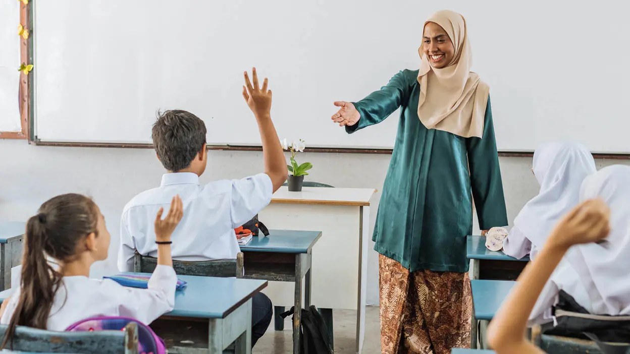 A teacher calling on a student raising their hand in class. 