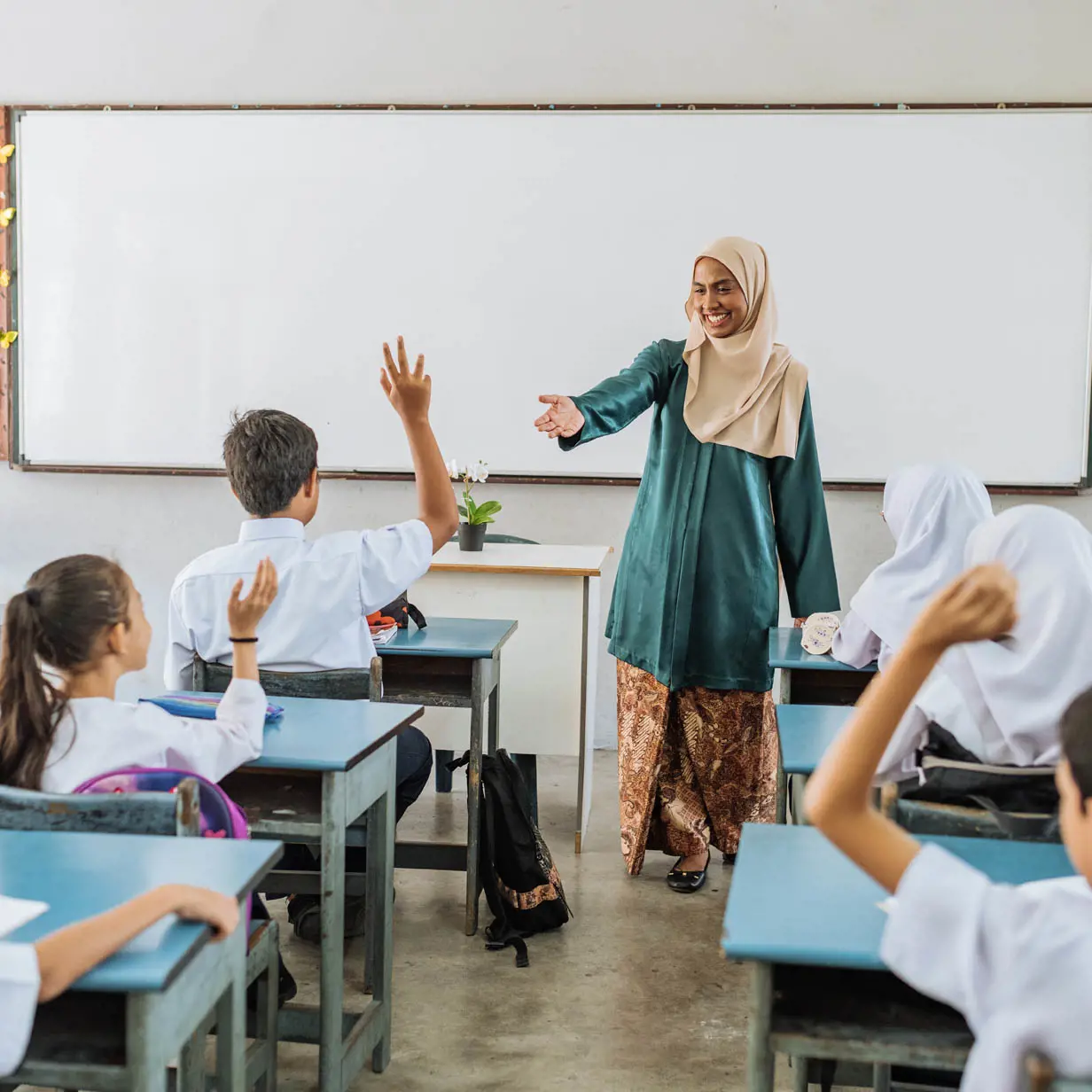 A teacher calling on a student raising their hand. 