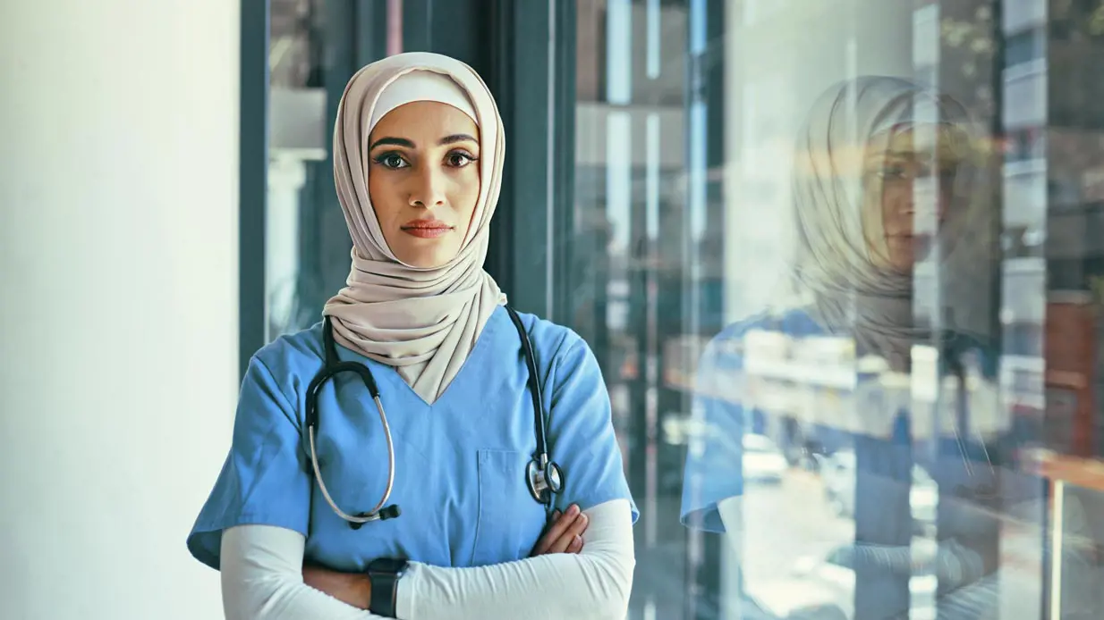 A medical professional wearing a hijab posing seriously for the camera. 