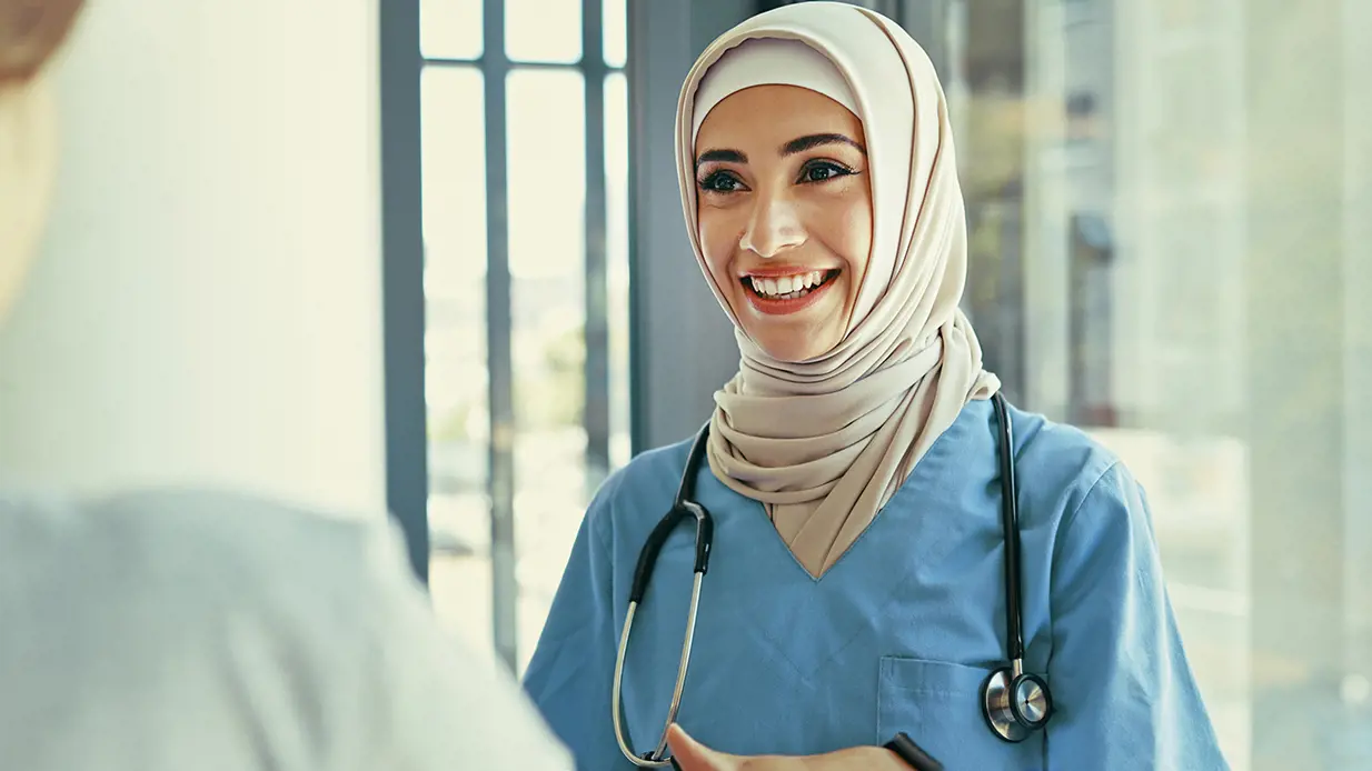 A doctor in Middle Eastern uniform smiling at a patient. The doctor appears compassionate and approachable.