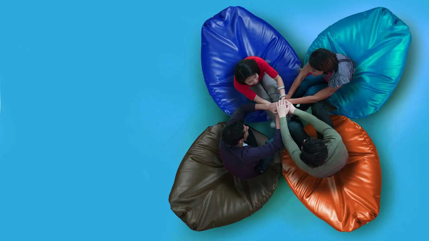 Four people sitting on Safety Pods, holding hands, symbolising support and solidarity through their connected and unified appearance.