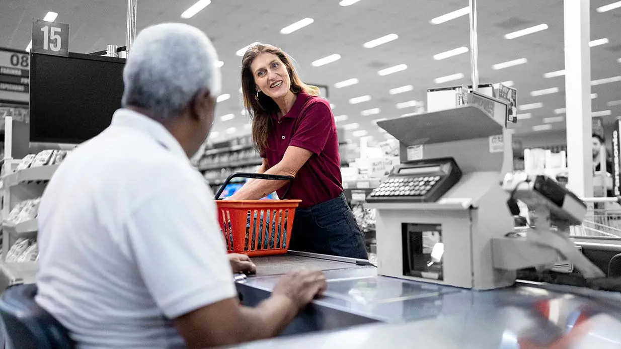 Retail worker checking out customer at register.