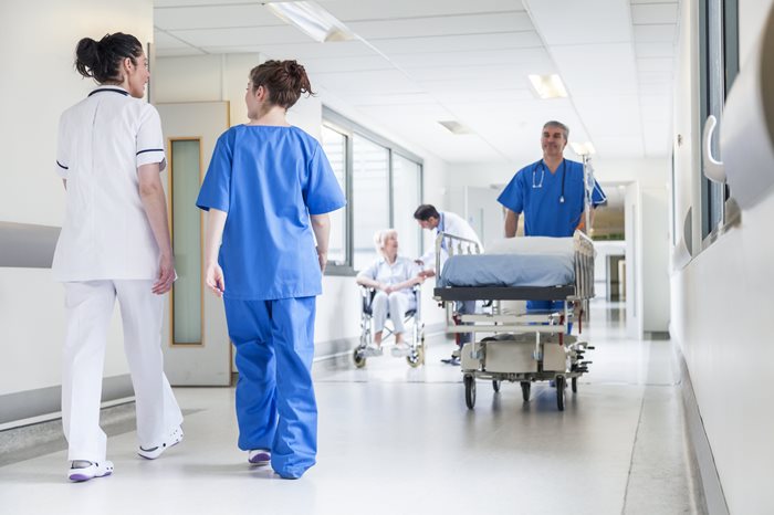 Two nurses and an orderly walking in a hospital hallway