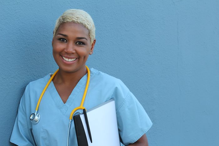 Smiling nurse leaning against a wall